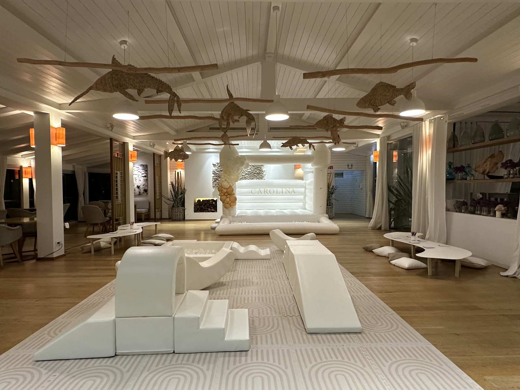 Espaço interior com soft play branco e castelo insuflável montados para uma festa